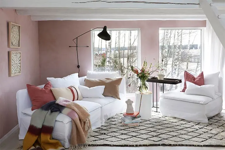 koselig liten stue med hvit sofa og rosa vegger