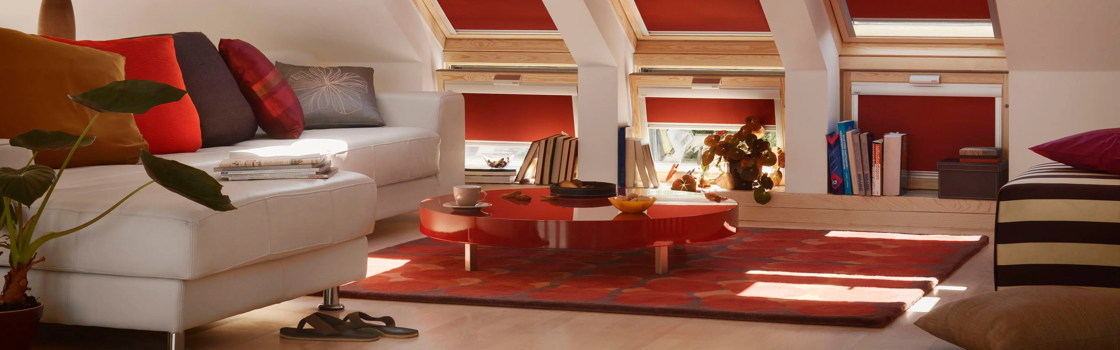 stue med sofa og mange takvinduer med rødfarget solskjerming