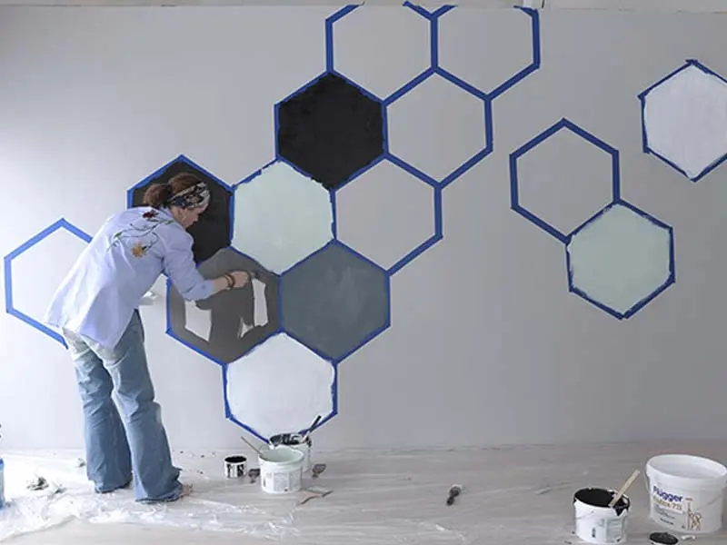 kvinne maler geometriske figurer på en Walls2paint-vegg